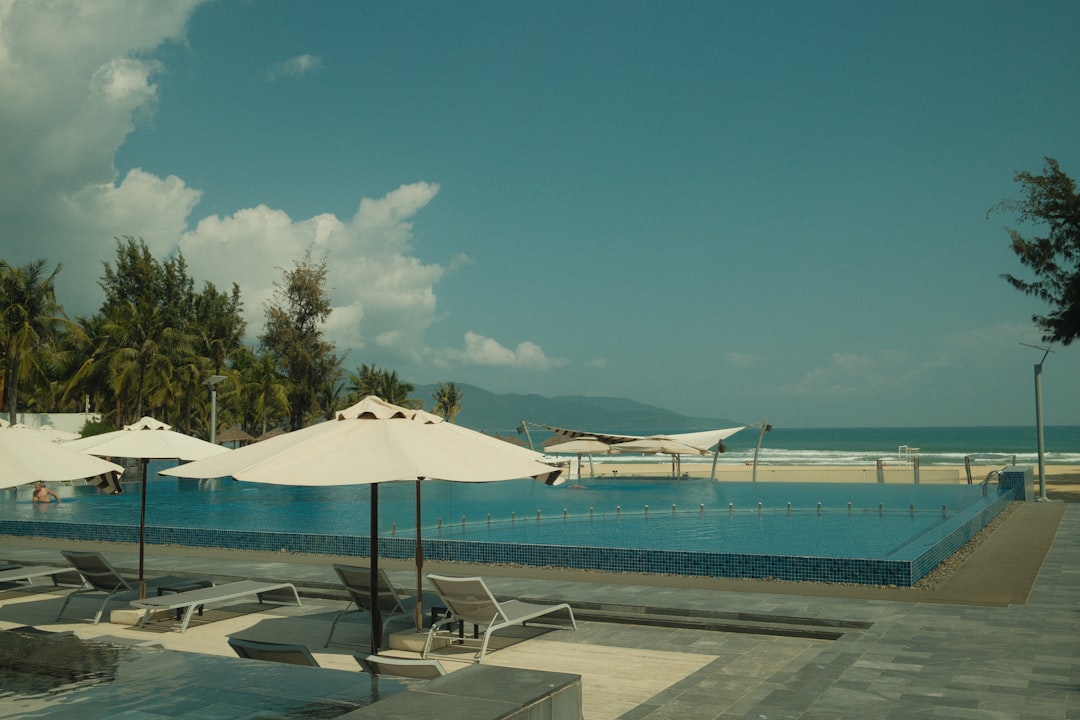 Modern luxury villa with a stunning infinity pool that seamlessly blends into the horizon of a clear blue ocean, represent...