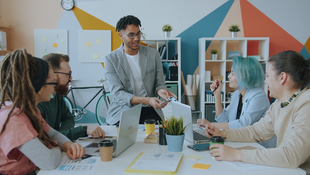 A diverse group of professionals collaborating around a table in a bright, minimalist office, showcasing the innovative spirit of Colorado Springs' tech startups.
